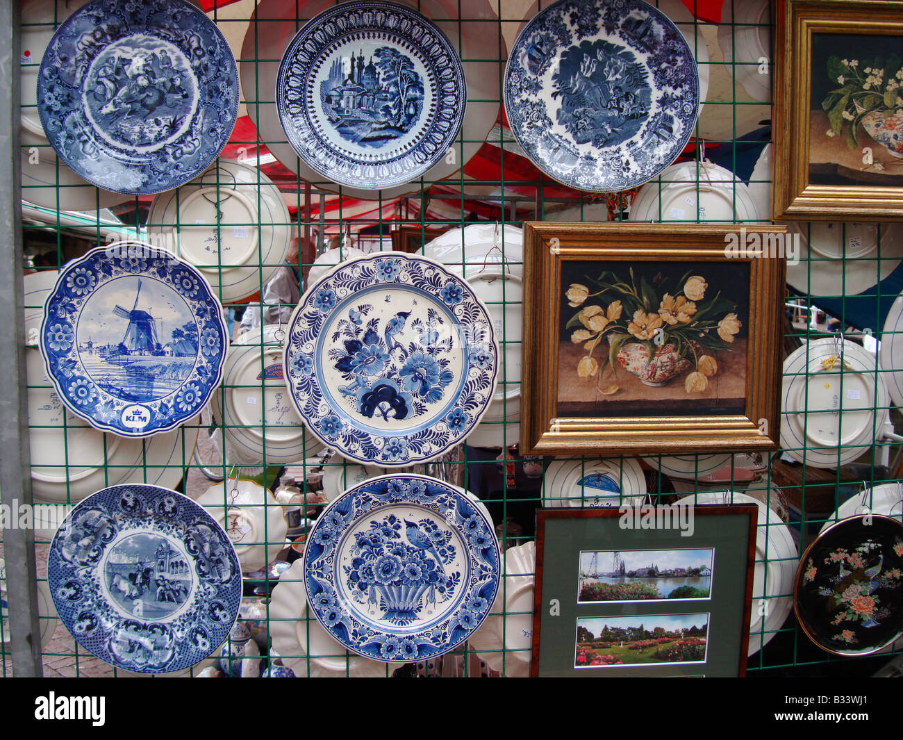 Delft blue crockery and paintings on display at market stall in Delft