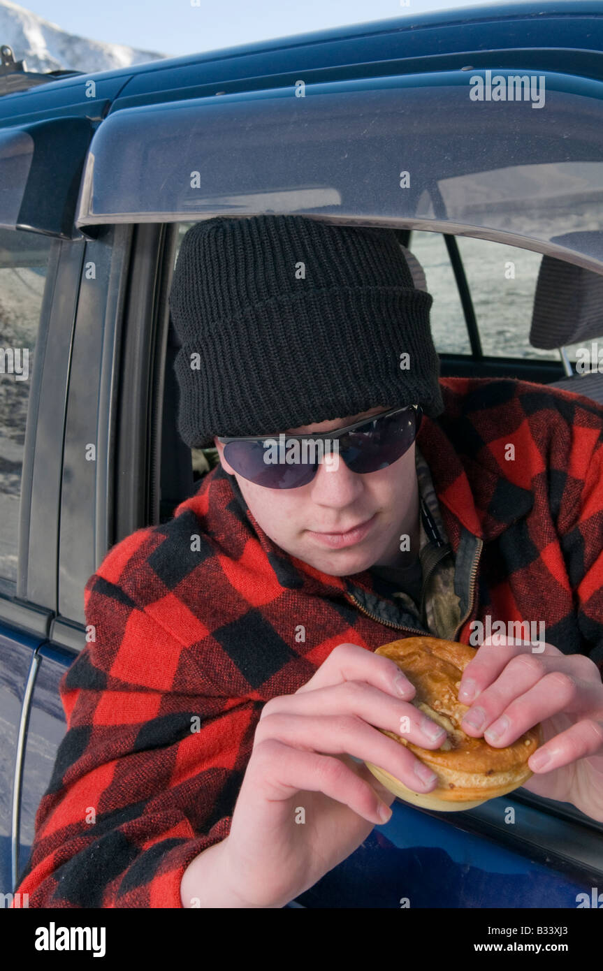 Young New Zealand farmer in truck eating a pie Stock Photo