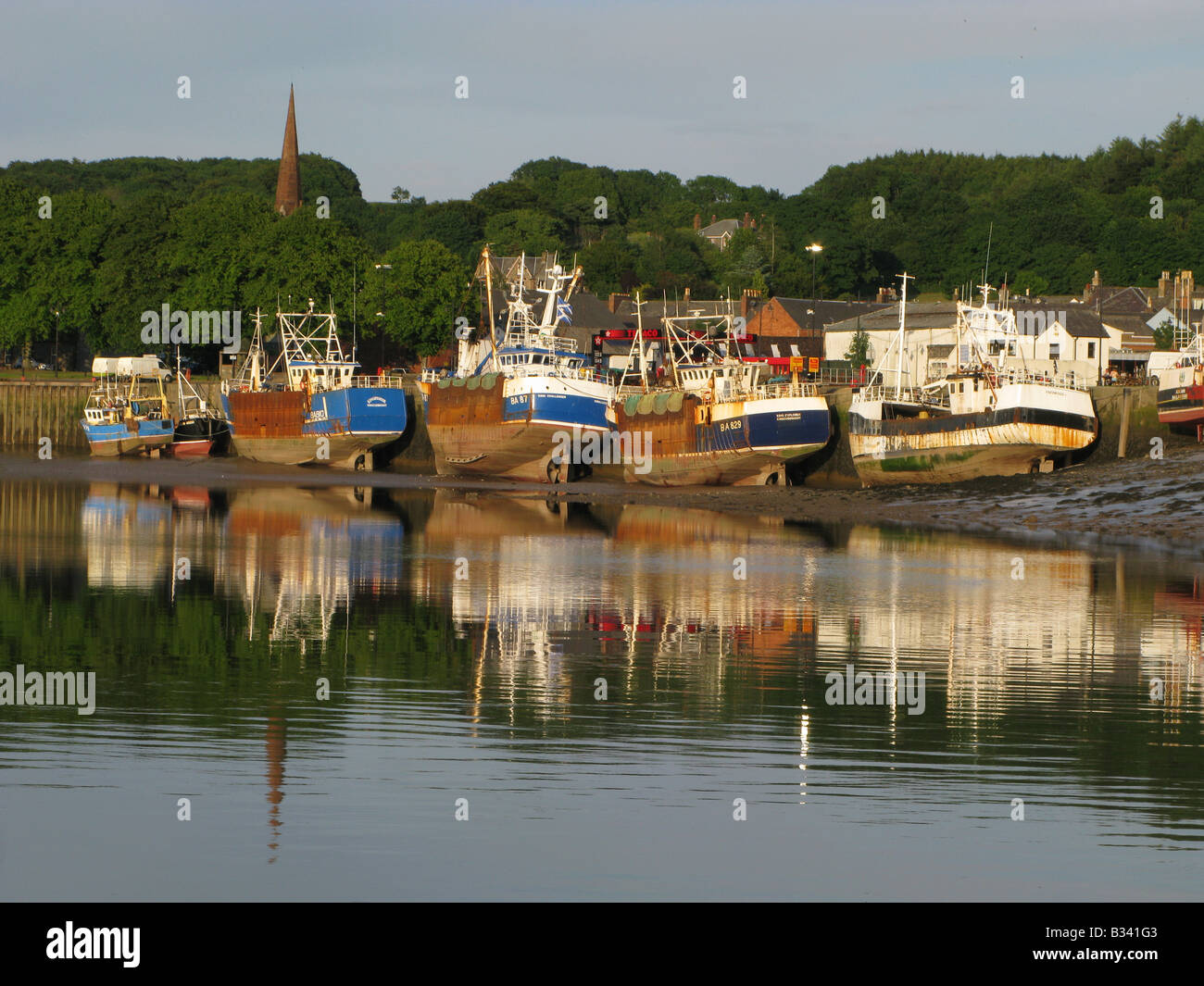 Low water in Kirkcudbright Harbour with the scallop boats tied up alongside the harbour wall Stock Photo