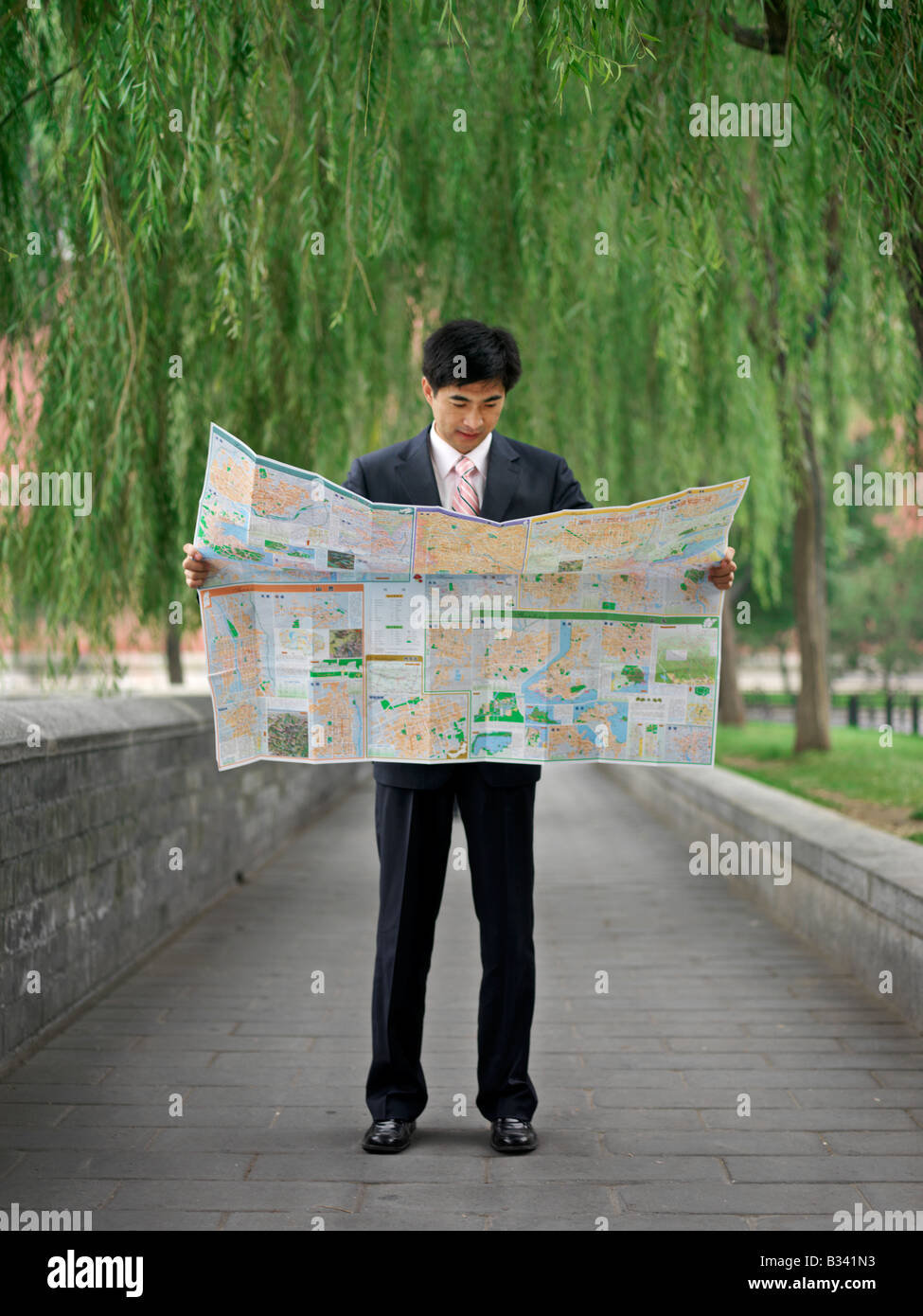 Chinese man looking at a map to help reorient or locate himself. Stock Photo