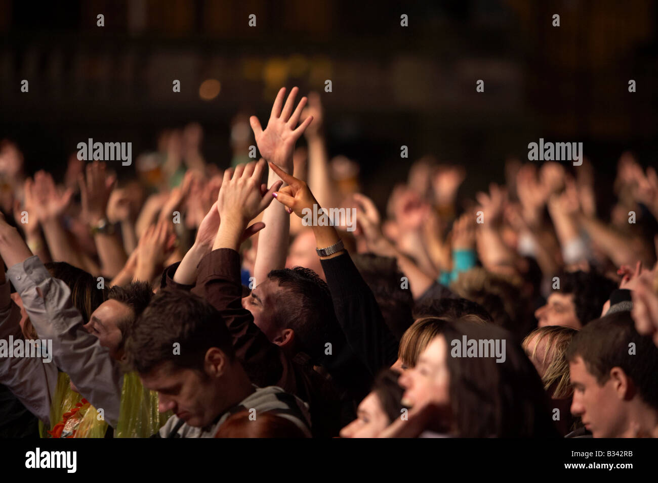 hands waving and pointing in a crowd of people during a nighttime concert in Belfast Stock Photo