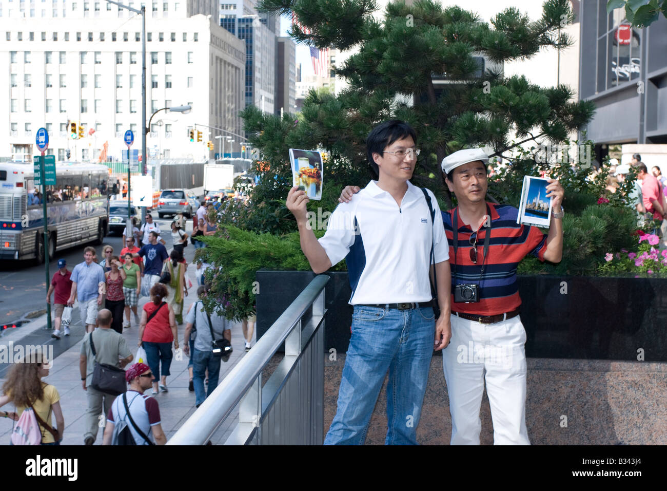 Two tourists smile and hold up pictures of the World Trade Center attack at the WTC site in Manhattan, NY. Stock Photo