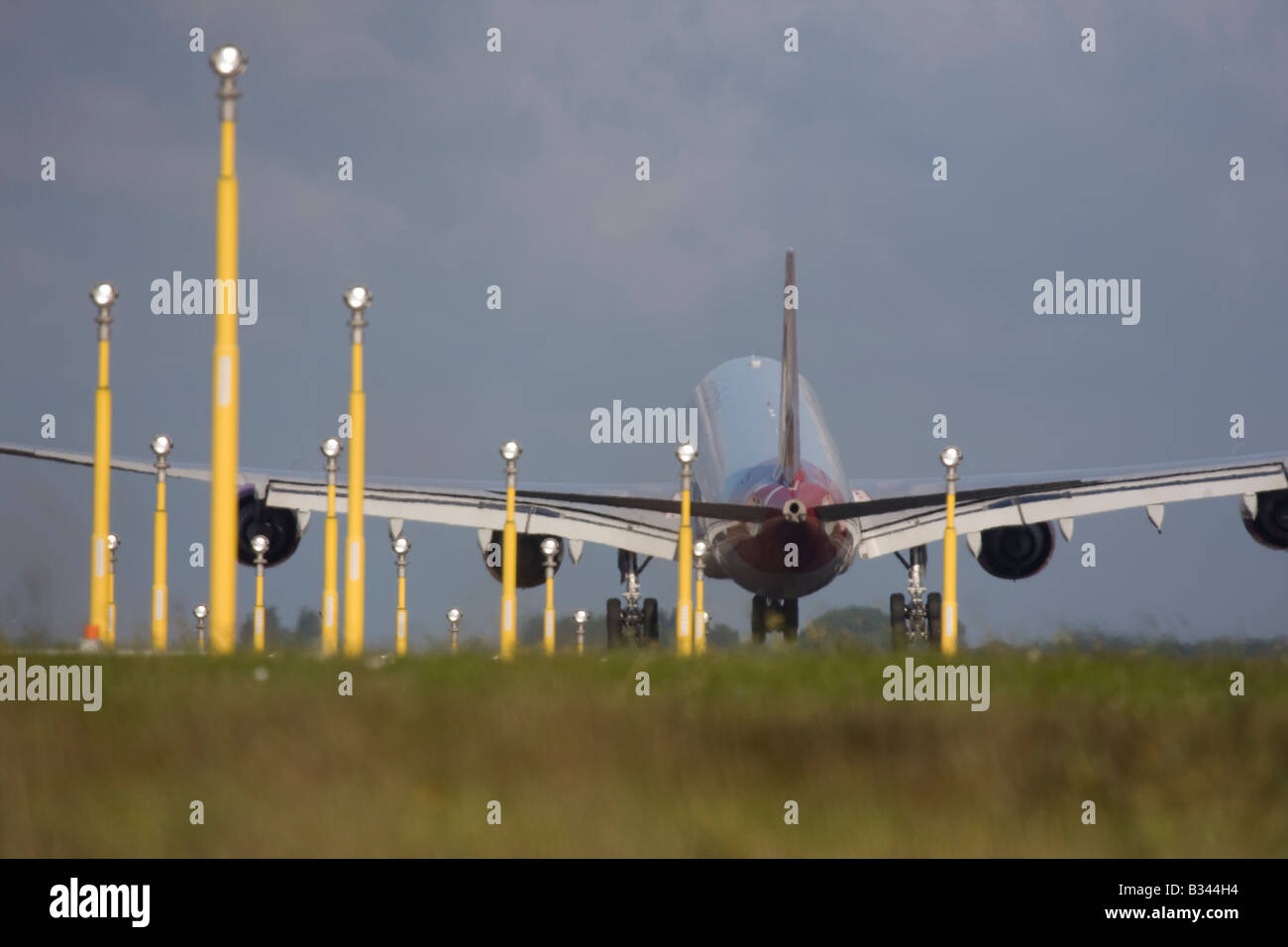Commercial aeroplane on short final approach to London Heathrow Airport with landing lights in the foreground. Stock Photo