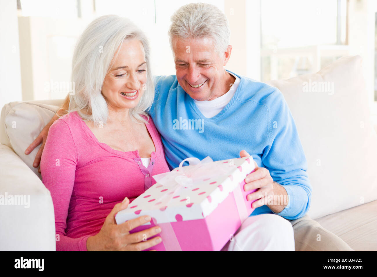 Husband giving wife gift in living room smiling Stock Photo Alamy