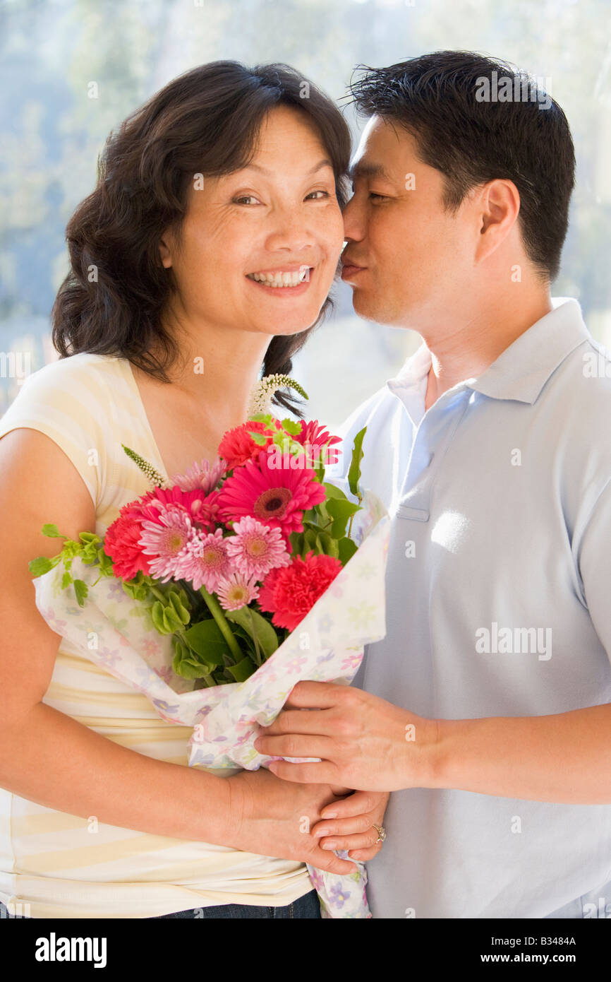 Husband and wife holding flowers kissing and smiling Stock Photo Alamy