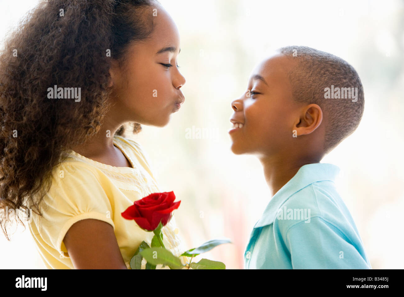Young boy giving young girl rose and smiling Stock Photo