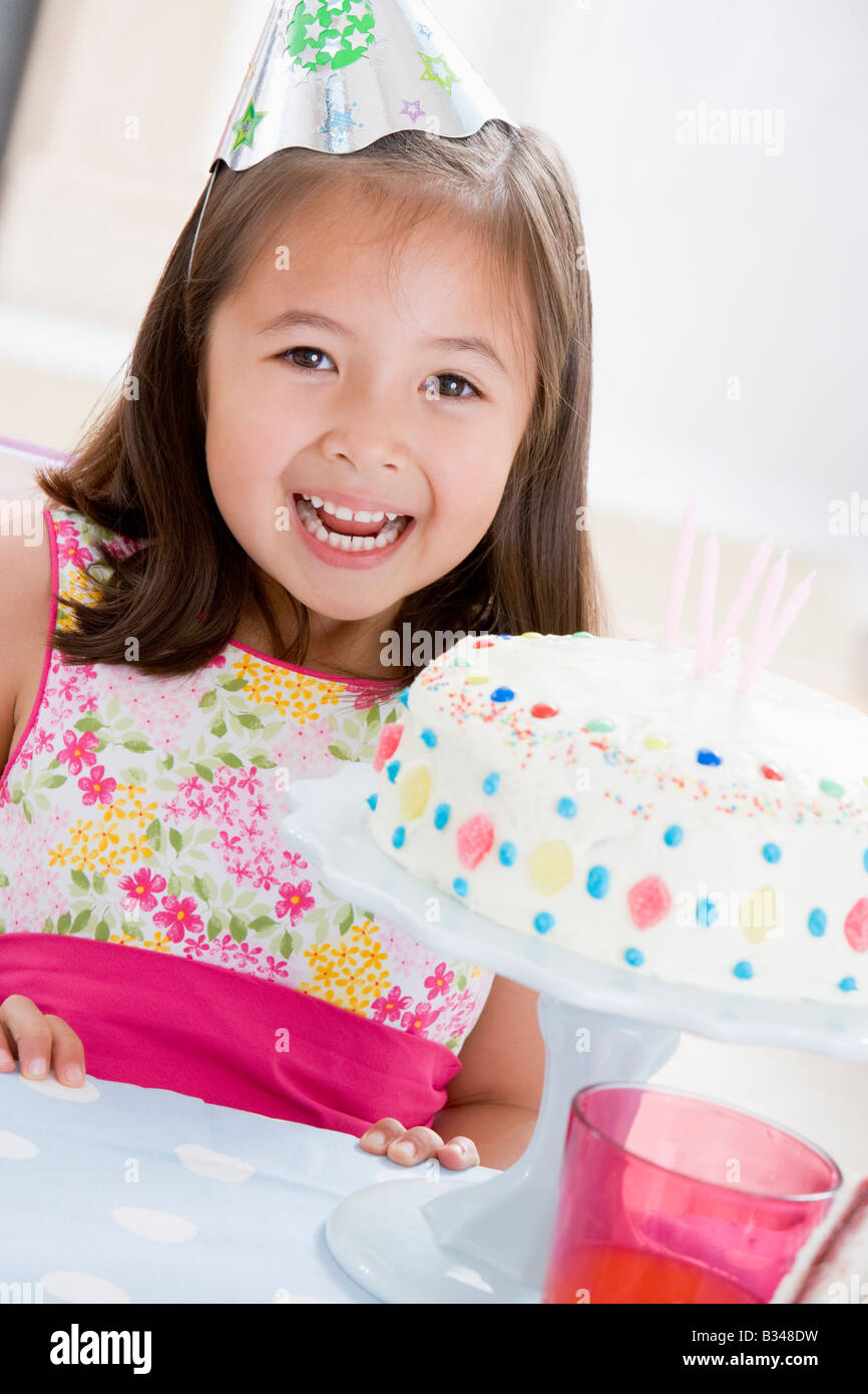 Young girl wearing party hat with birthday cake smiling Stock Photo - Alamy