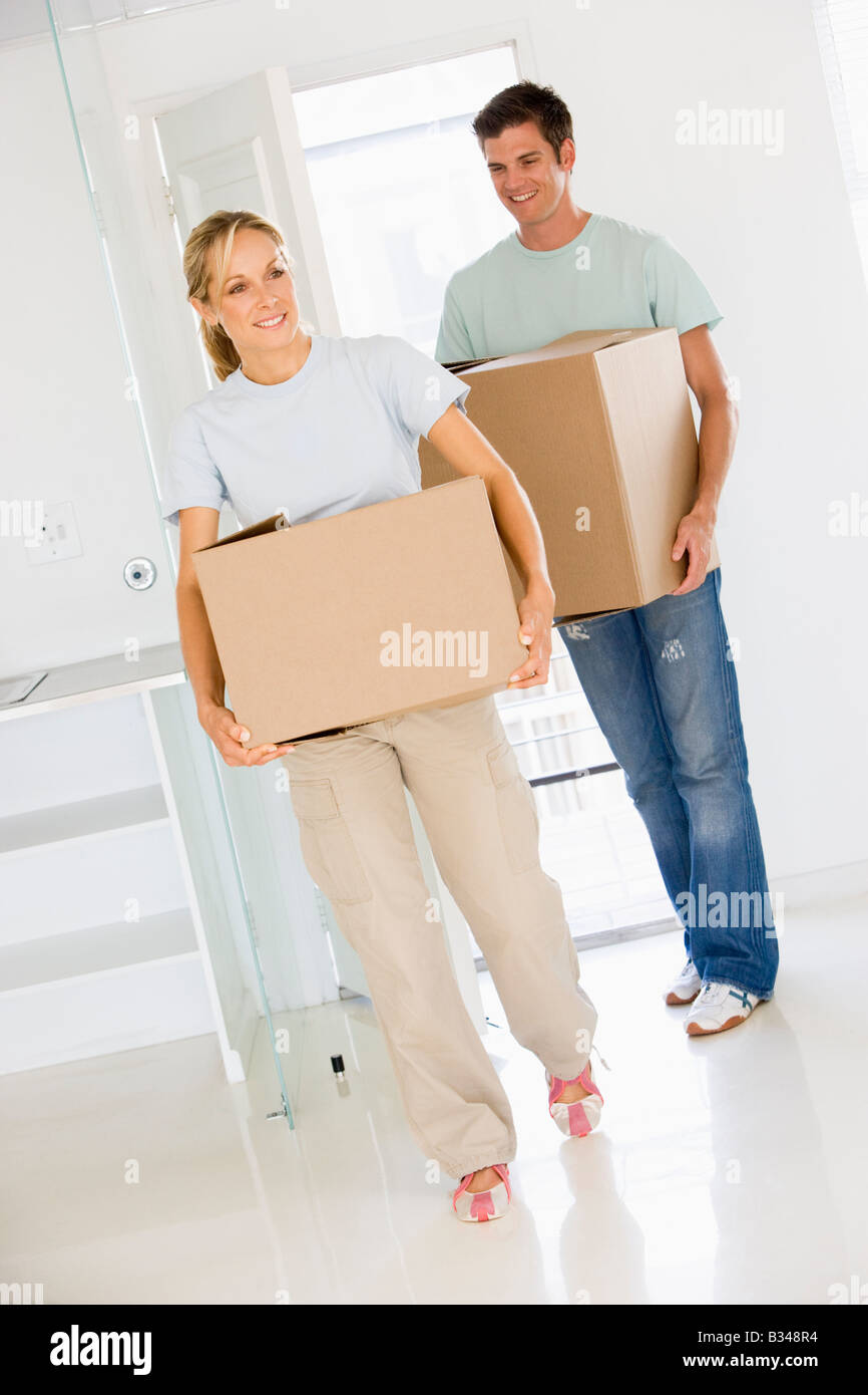 Couple with boxes moving into new home smiling Stock Photo - Alamy