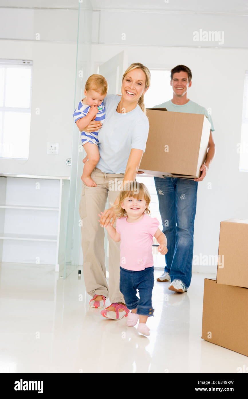 Family with box moving into new home smiling Stock Photo - Alamy