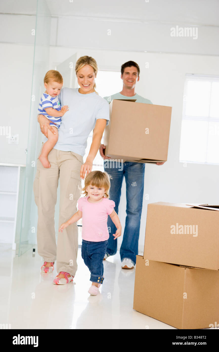 Family with box moving into new home smiling Stock Photo - Alamy