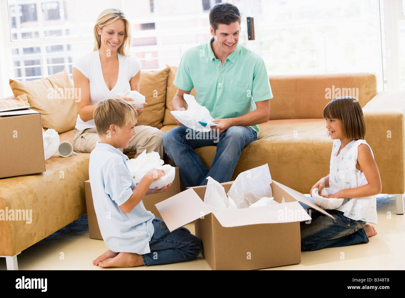 Family unpacking boxes in new home smiling Stock Photo Alamy