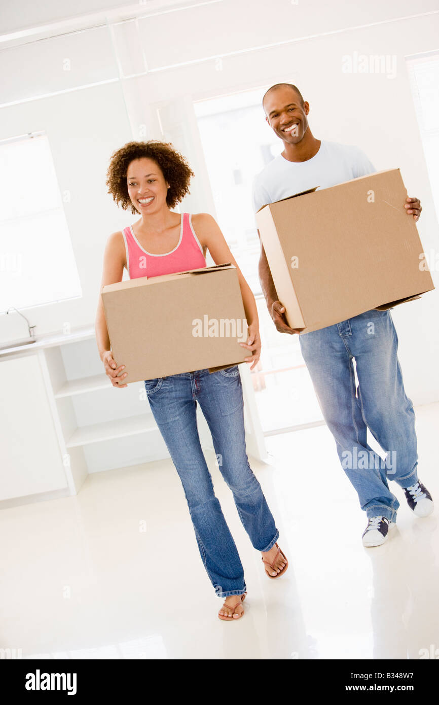 Couple with boxes moving into new home smiling Stock Photo - Alamy