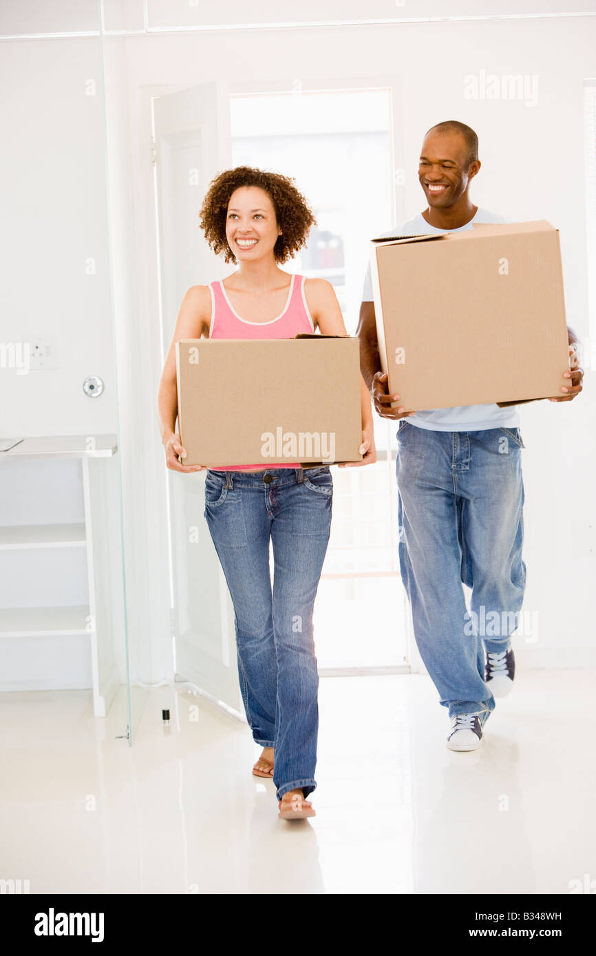 Couple with boxes moving into new home smiling Stock Photo - Alamy