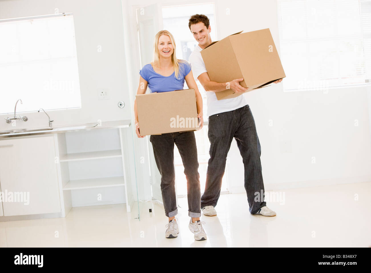 Couple with boxes moving into new home smiling Stock Photo - Alamy