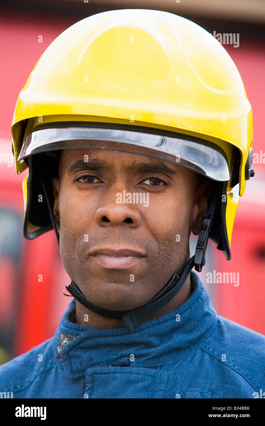 Fireman standing by fire engine wearing helmet Stock Photo