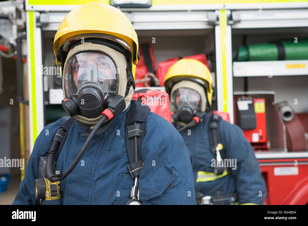 Two firemen in masks standing near fire engine (depth of field) Stock Photo