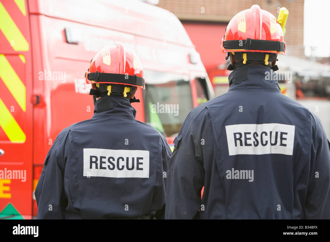 Two rescue workers standing near rescue vehicle Stock Photo