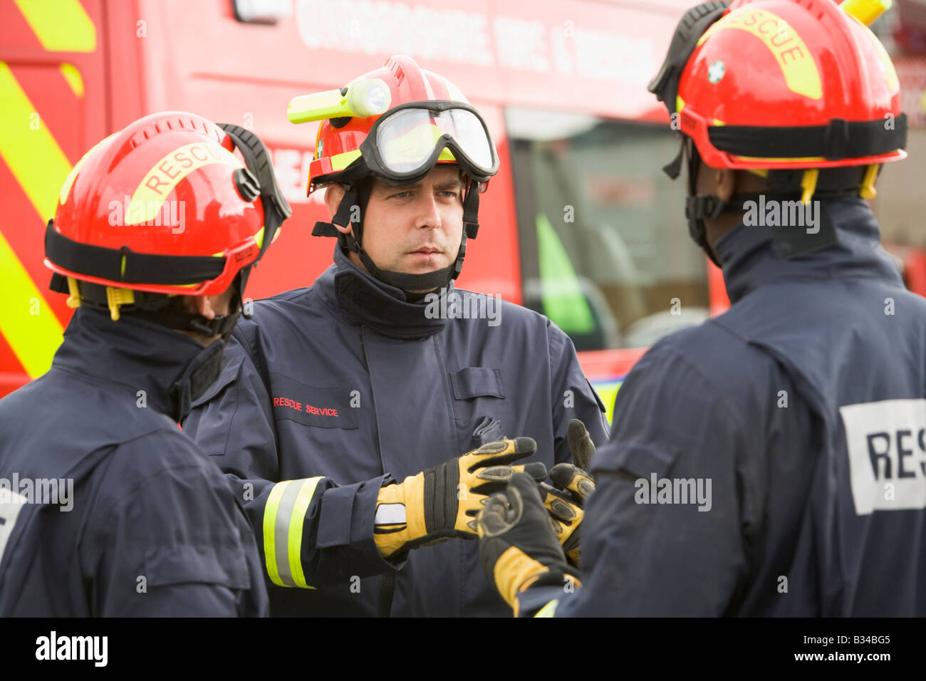 Three rescue workers talking by rescue vehicle Stock Photo
