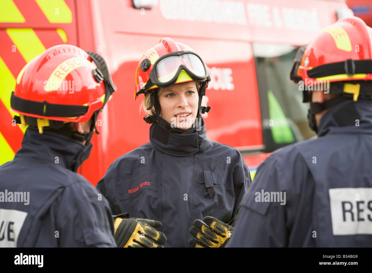 Three rescue workers talking by rescue vehicle Stock Photo