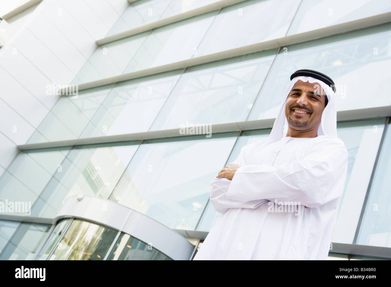 Businessman standing outdoors by building smiling Stock Photo