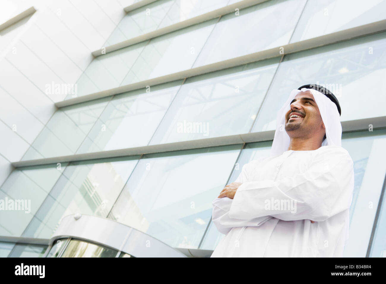 Businessman standing outdoors by building smiling Stock Photo