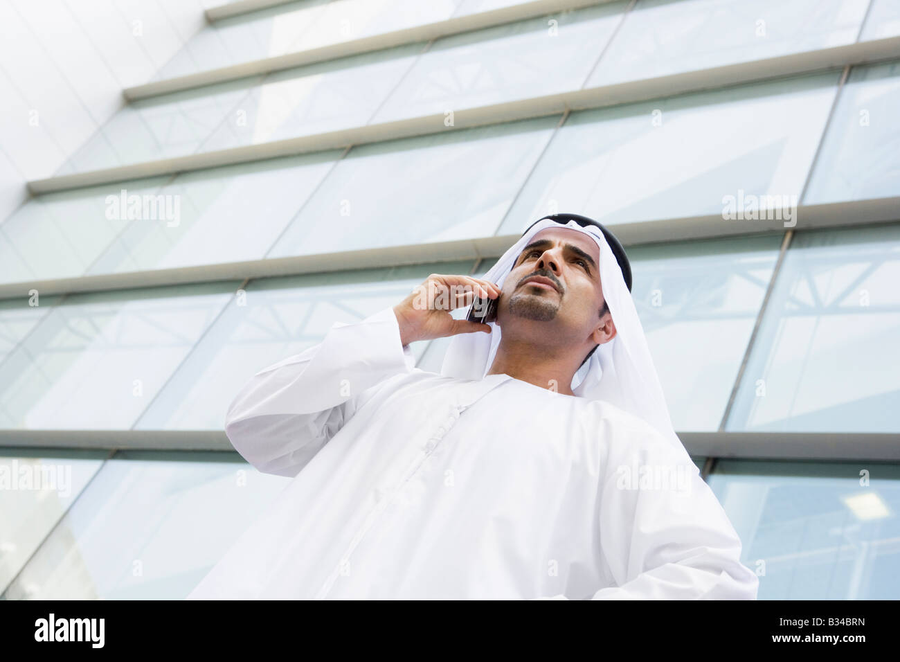 Businessman standing outdoors by building on cellular phone (selective focus) Stock Photo
