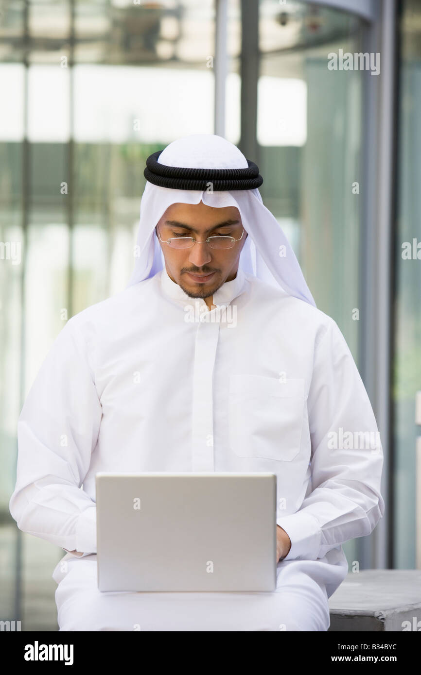 Businessman sitting outdoors with laptop by building (selective focus) Stock Photo