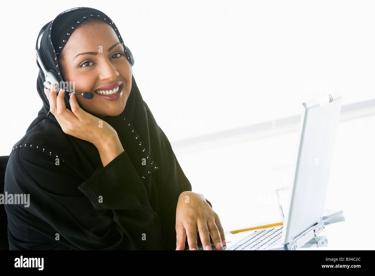 Woman wearing headset with laptop smiling (high key/selective focus) Stock Photo