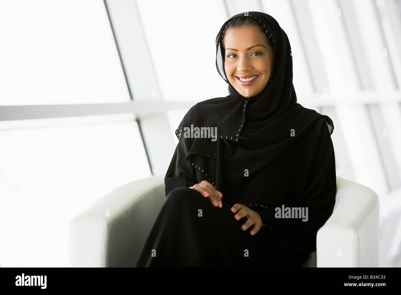 Woman sitting indoors smiling (high key/selective focus) Stock Photo