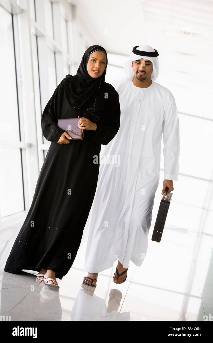 Two businesspeople walking in a corridor and smiling (high key/selective focus) Stock Photo