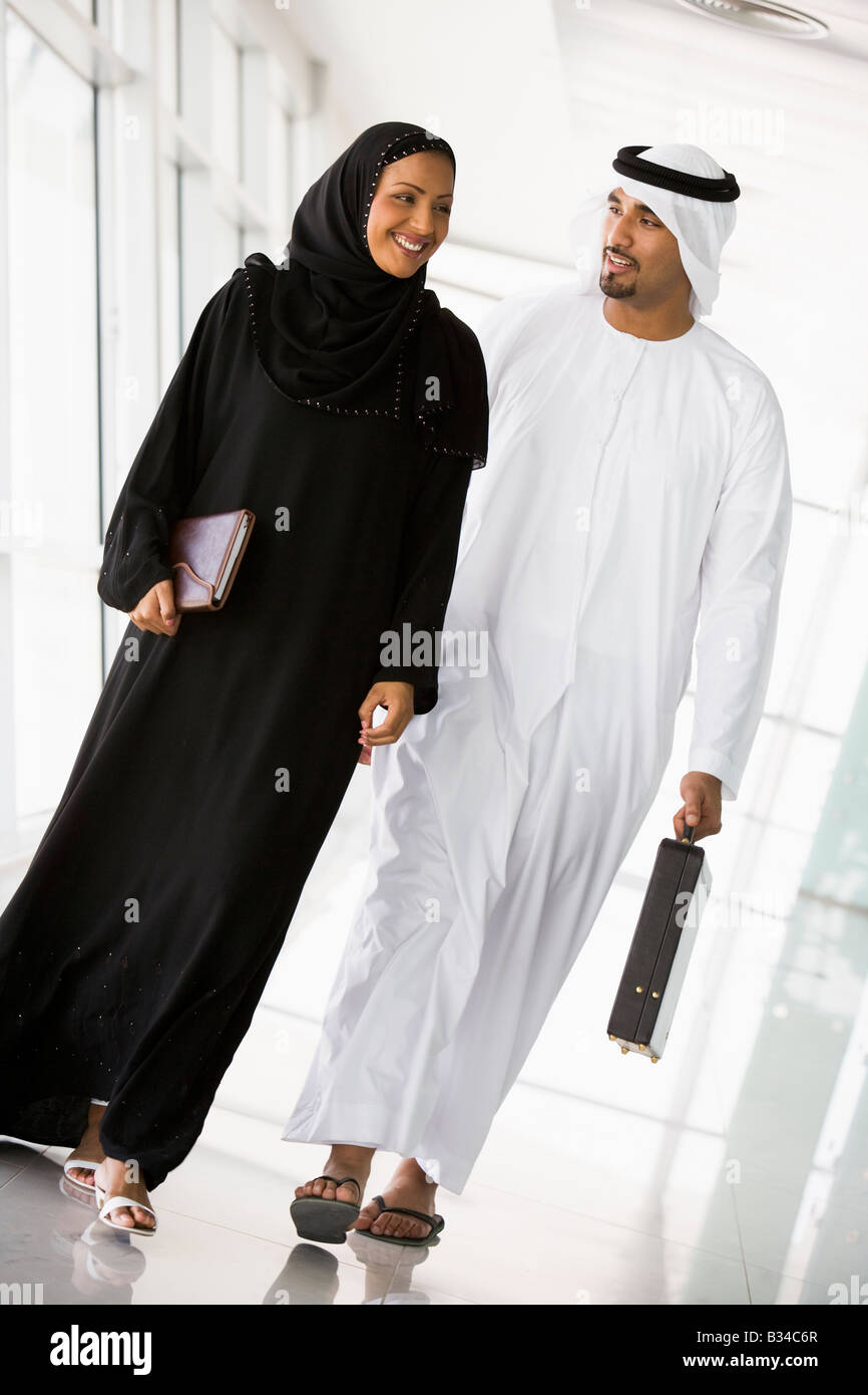 Two businesspeople walking in a corridor and smiling (high key/selective focus) Stock Photo