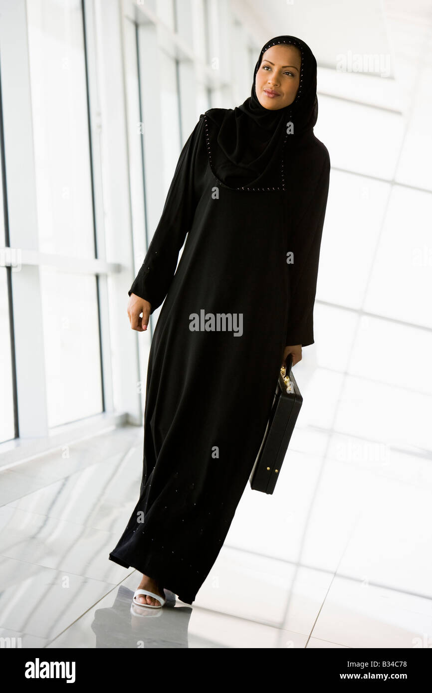 Businesswoman walking in a corridor with a briefcase and smiling (high key/selective focus) Stock Photo