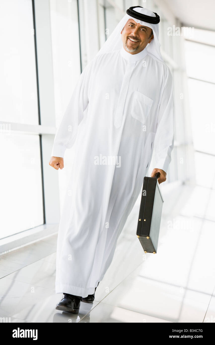 Businessman walking in a corridor with a briefcase smiling (high key/selective focus) Stock Photo