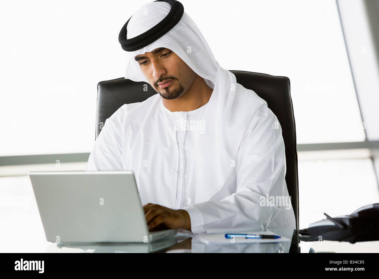 Businessman in office with laptop working (high key/selective focus) Stock Photo