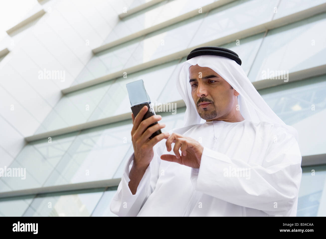 Businessman outdoors by building using PDA Stock Photo