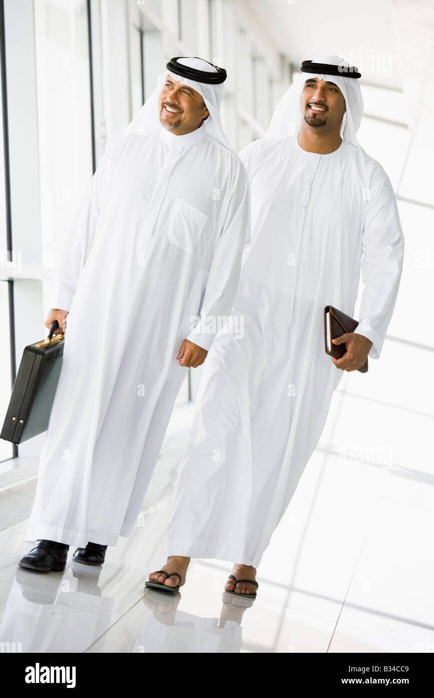 Two businessmen walking in corridor smiling (high key/selective focus) Stock Photo