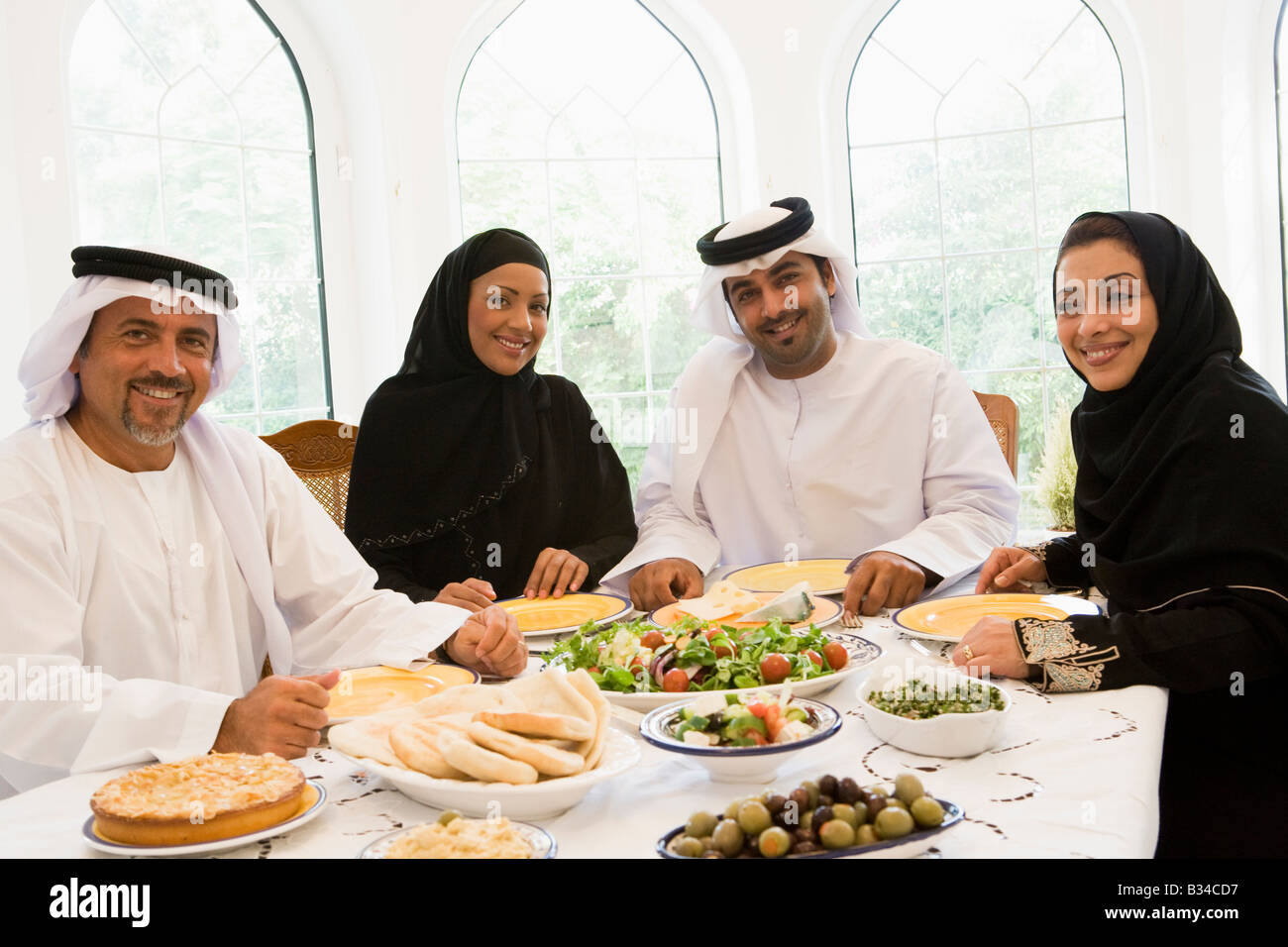 Two couples sitting at dinner table smiling (high key) Stock Photo