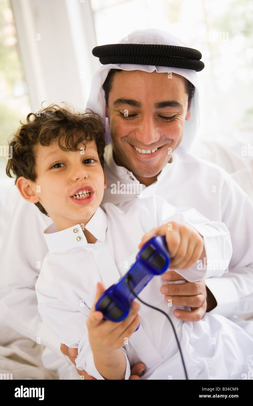 Father and son in living room playing video games and smiling (high key/selective focus) Stock Photo
