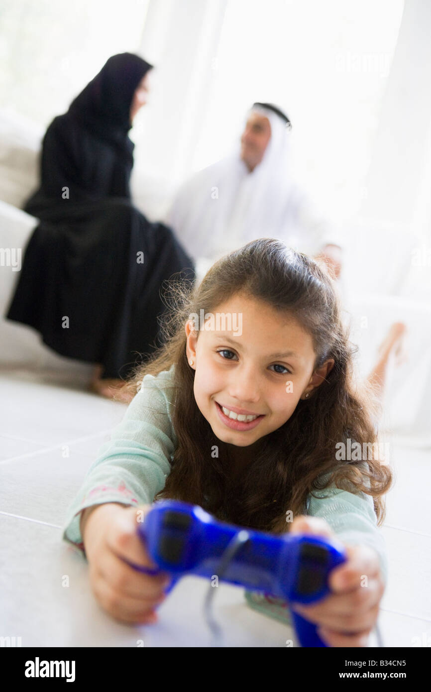 Daughter in living room playing video games smiling with parents in background (high key/selective focus) Stock Photo