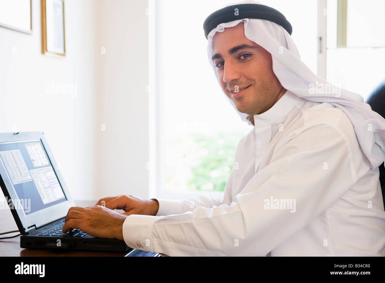 Man in office with laptop smiling (high key/selective focus) Stock Photo