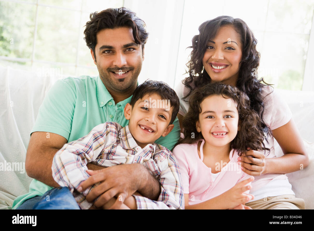 Family in living room sitting on sofa smiling (high key) Stock Photo