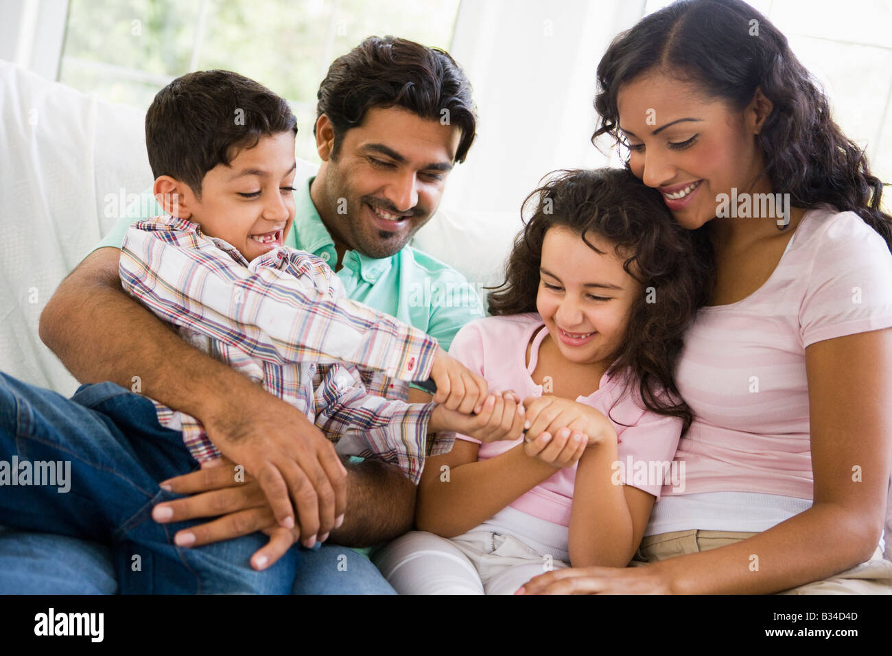 Family in living room fighting over remote control smiling (high key) Stock Photo