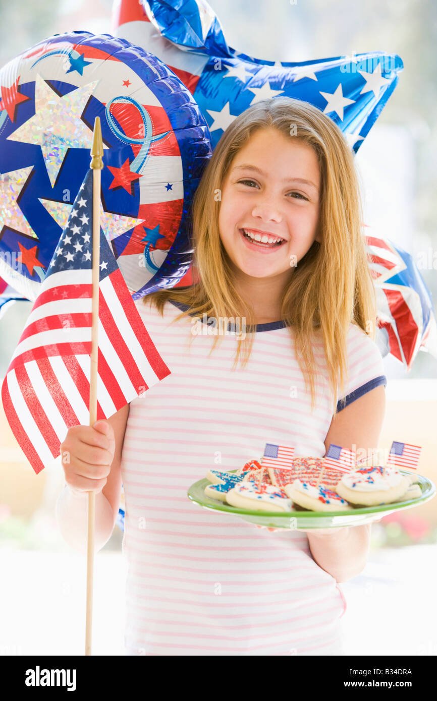Young girl outdoors on fourth of July with flag and cookies smiling Stock Photo