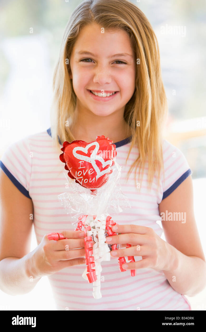 Young girl on Valentine's Day holding love themed balloon smiling Stock Photo