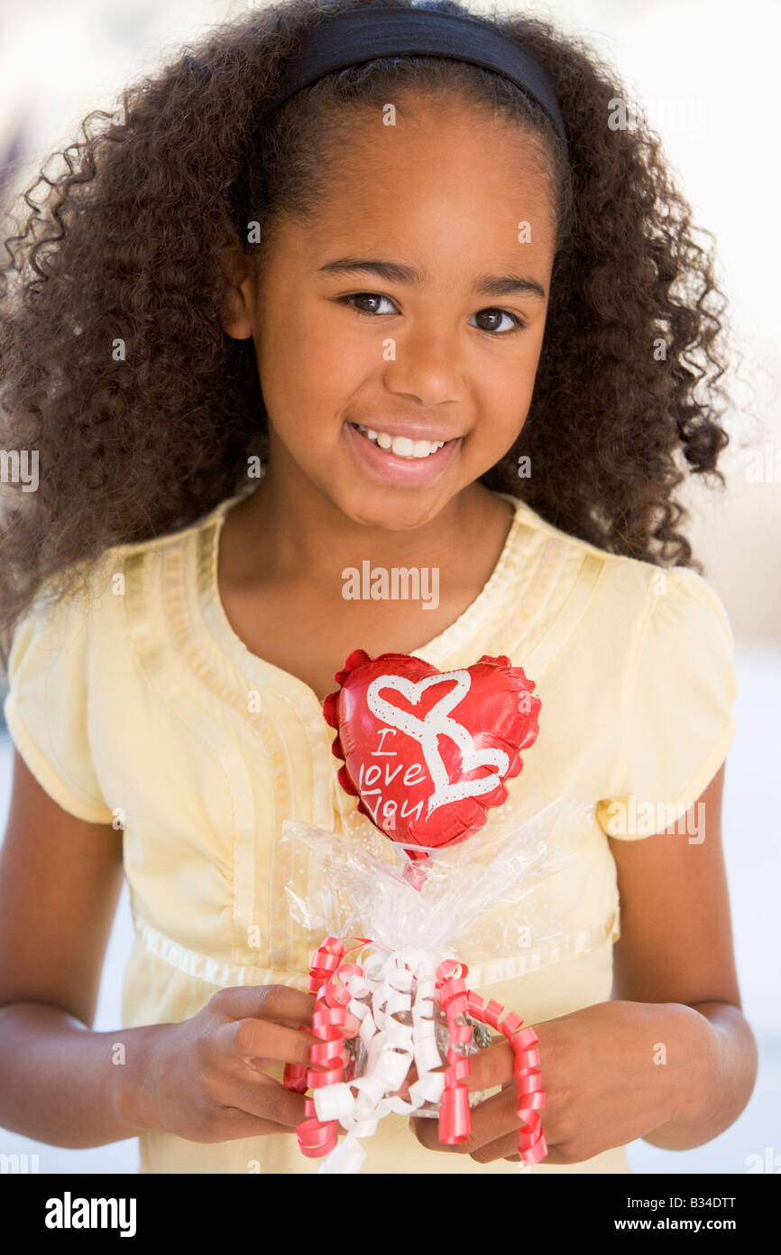 Young girl on Valentine's Day holding love themed balloon smiling Stock Photo