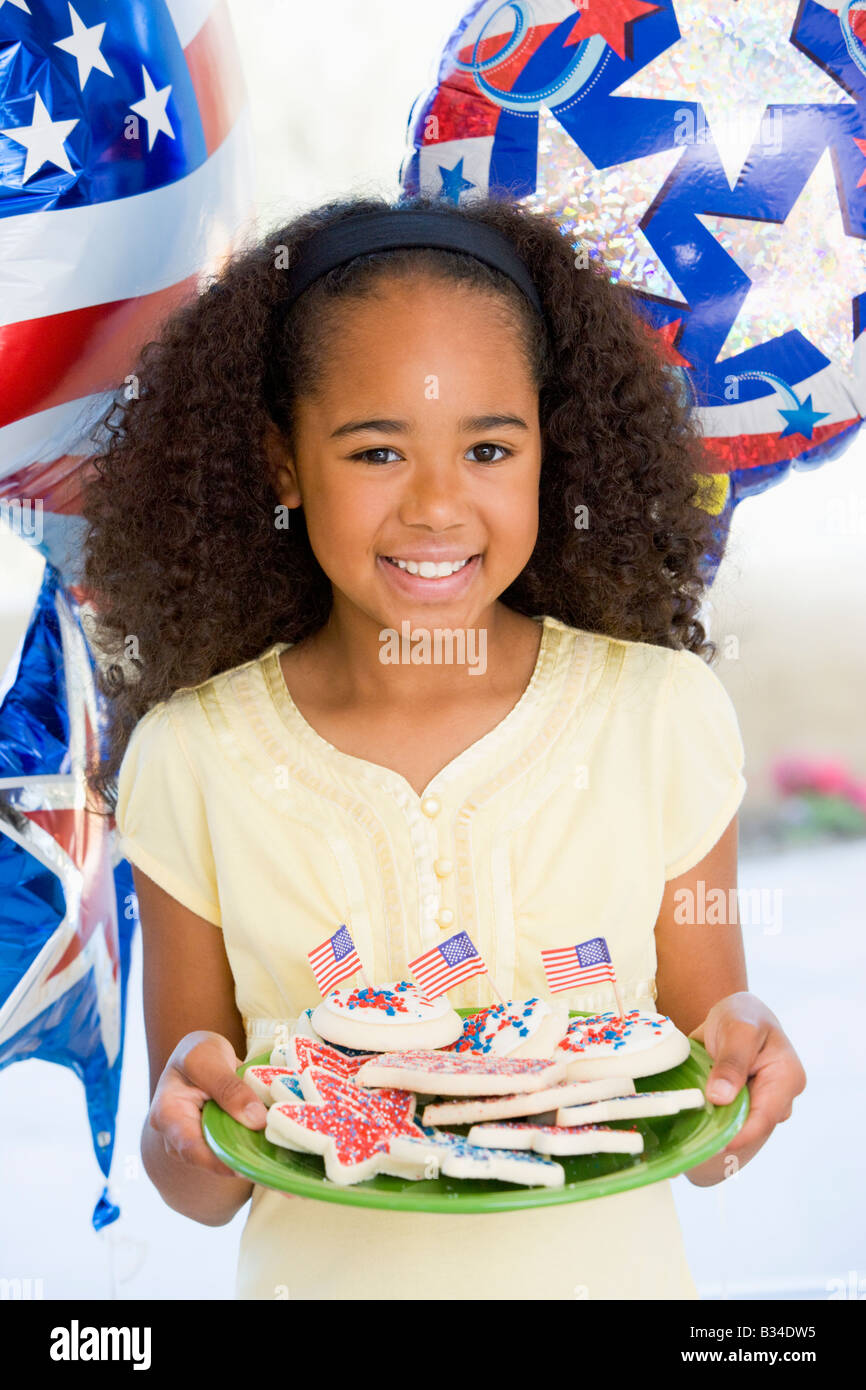 Young girl on fourth of July with balloons and cookies smiling Stock Photo
