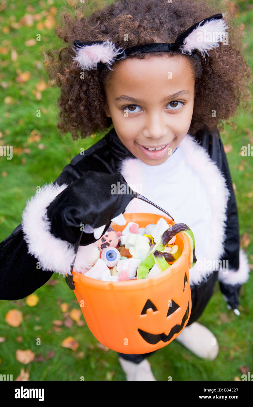 Young girl outdoors in cat costume on Halloween holding candy Stock Photo
