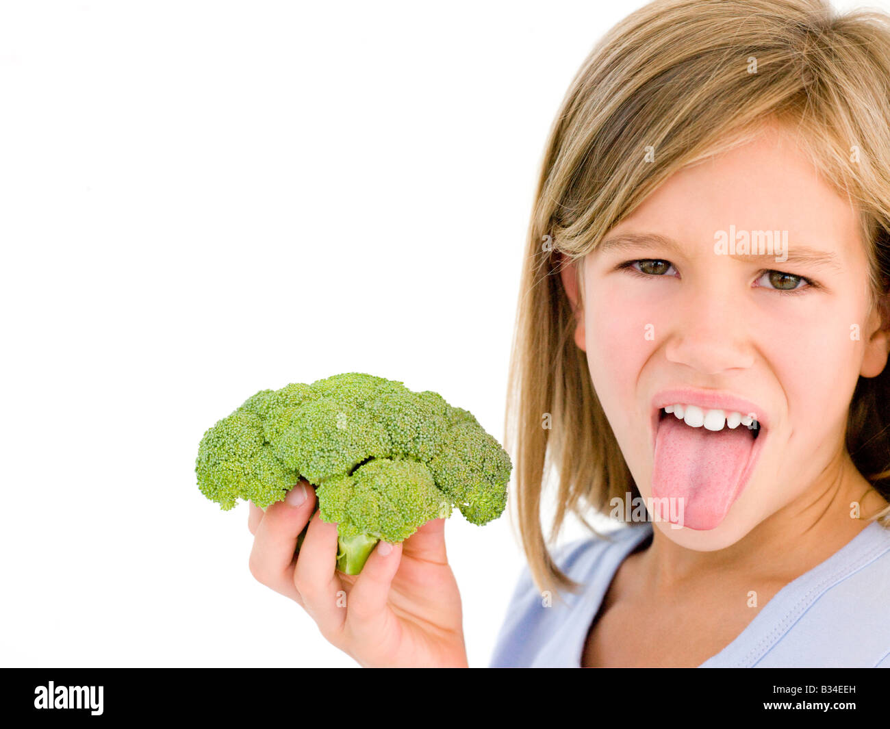 Young girl holding broccoli and sticking tongue out Stock Photo Alamy