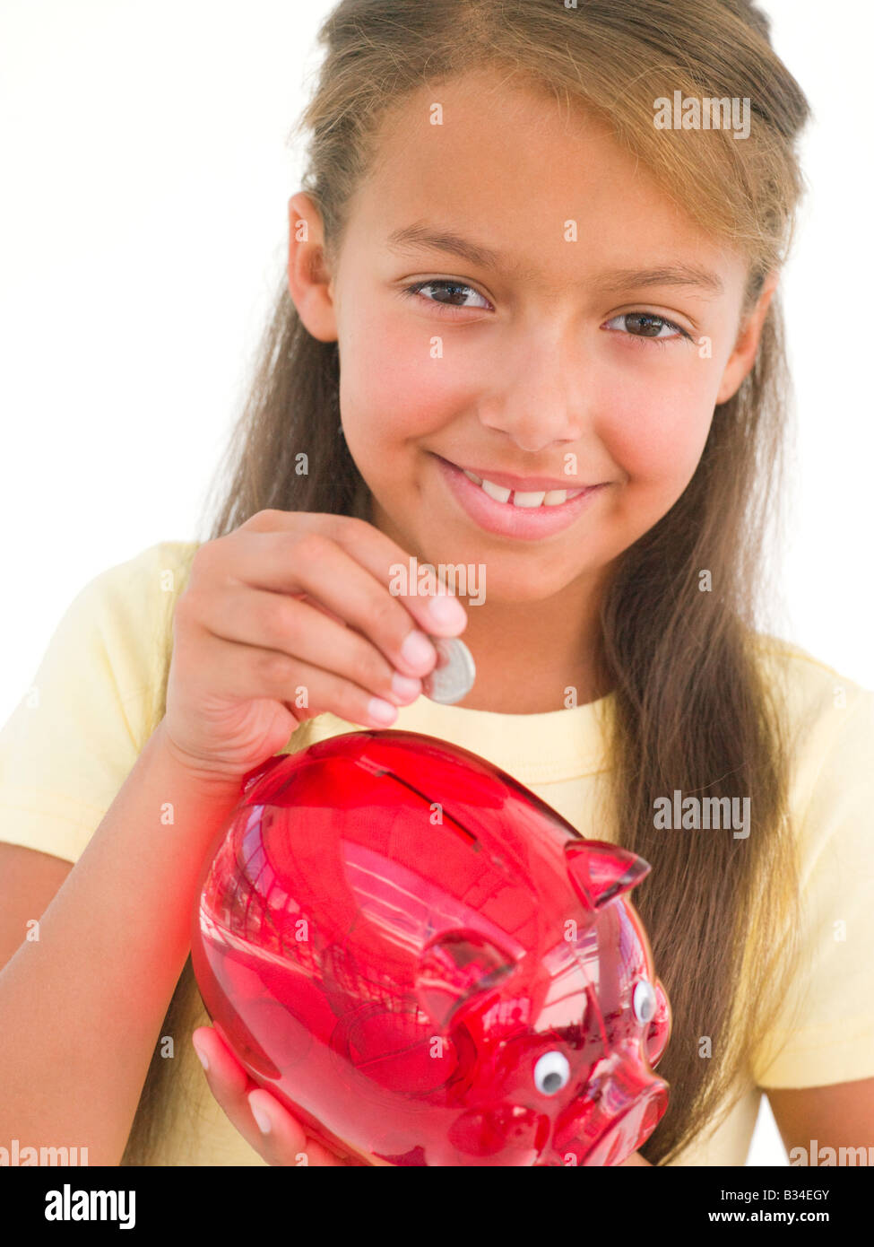 Young girl putting coin into piggy bank smiling Stock Photo - Alamy