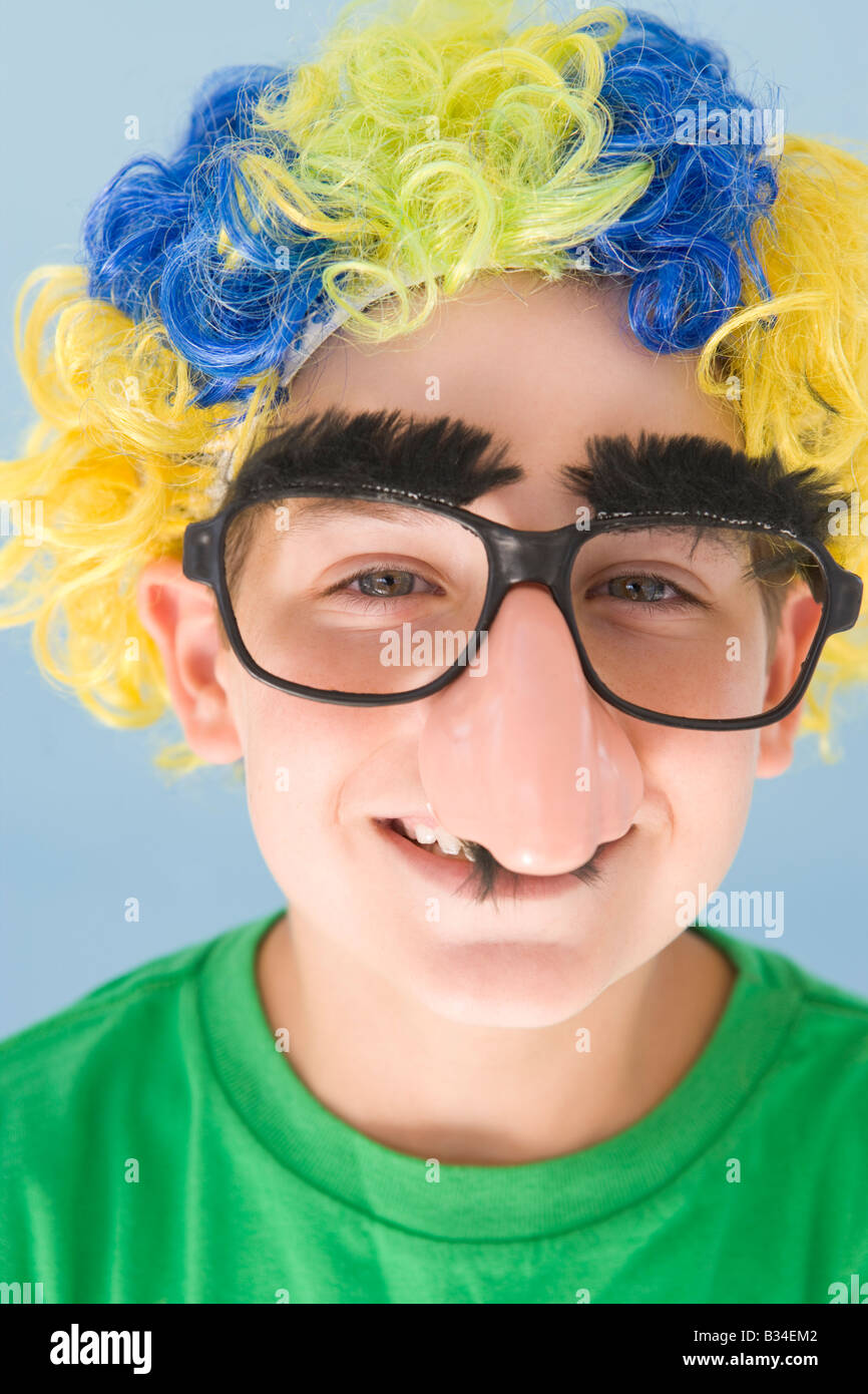 Young boy wearing clown wig and fake nose smiling Stock Photo